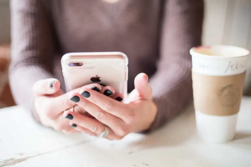 Customer checking a phone with a coffee